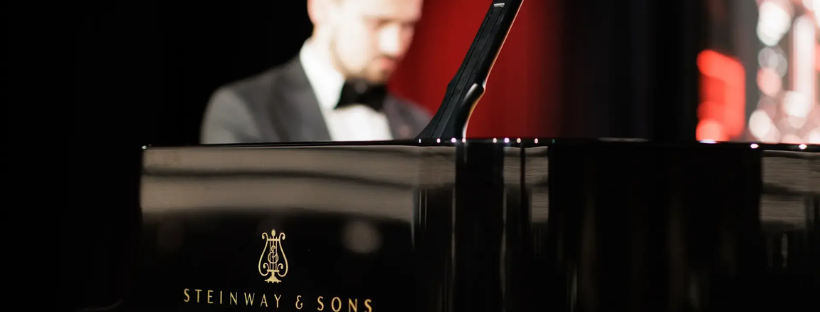 Pianiste en tenue de soir&eacute;e derri&egrave;re un piano Steinway.